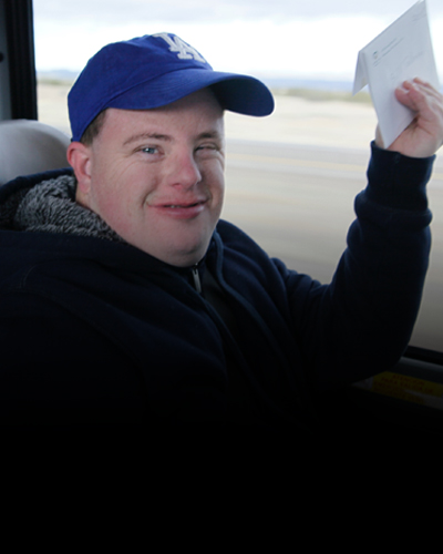 Person in a black hoodie and blue baseball hat riding in a car.