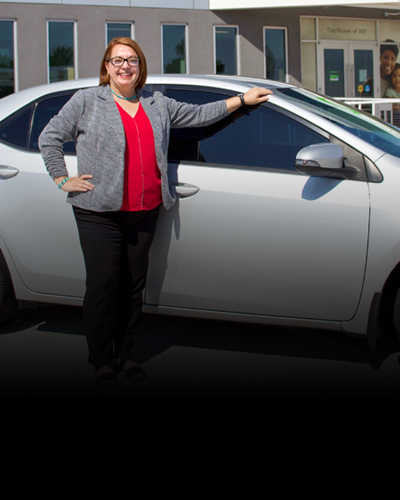 Person standing in front of a white car outside of Nusenda