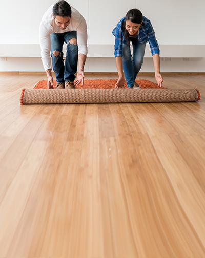 Couple unrolling a rug on a wood floor